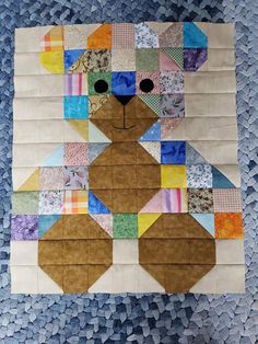 a teddy bear made out of patchwork material on top of blue and white paper