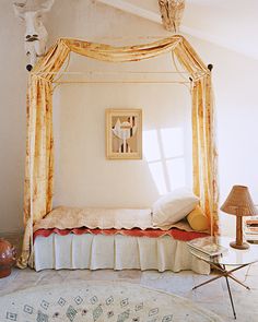 a canopy bed in a bedroom with an orange drape on the headboard and foot board