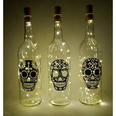 three bottles with lights in them that have skulls on them