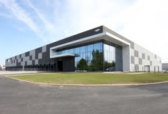 an empty parking lot in front of a large building with glass windows on the side