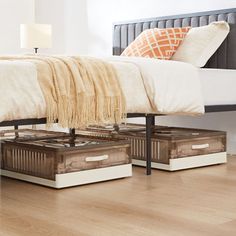 a bed with two boxes underneath it on the floor next to a lamp and pillows