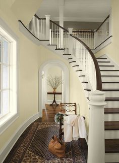 an entryway with stairs and rugs on the floor in front of it is painted yellow