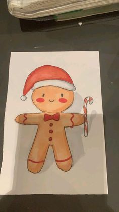 a drawing of a gingerbread man with a santa hat and candy cane in his hand