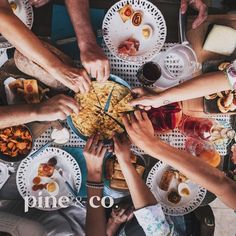 a group of people sitting around a table with food and drinks on it, top view