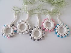 three different colored beads are hanging from the side of a white table with green plants