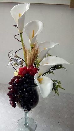 a vase filled with flowers and berries on top of a table