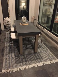 a dining room table with chairs and a rug in front of it