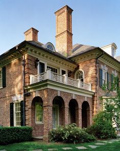 an old brick house with two chimneys and balconies on the second floor is shown