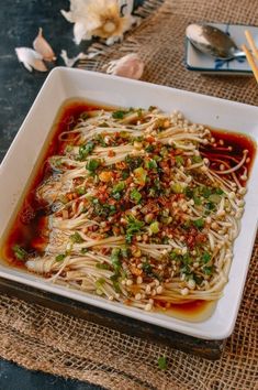 a white plate topped with noodles and sauce on top of a table next to chopsticks