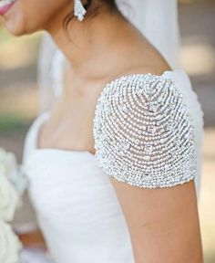 a woman in a wedding dress with pearls on her arm