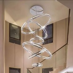 a modern chandelier hanging from the ceiling in a living room next to stairs