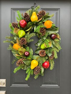 a wreath with fruit and pine cones on the front door