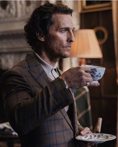 a man in a suit holding a cup and saucer