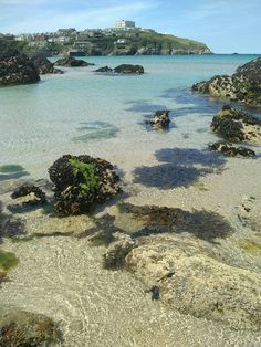 the water is crystal blue and clear with rocks in front of it that are surrounded by green plants