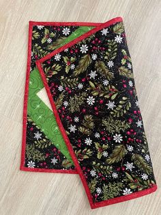 two pieces of fabric on top of each other, one with green and red trim