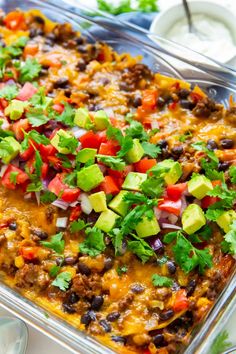 a casserole dish filled with black beans, avocado and cilantro