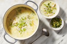 two bowls filled with soup on top of a white counter next to silver spoons