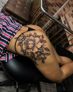 a woman with a flower tattoo on her thigh sitting in a chair next to stairs