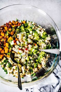 a bowl filled with broccoli, cauliflower and other vegetables next to a spoon