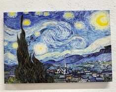 the painting is hanging on the wall in front of a white wall with a blue sky and yellow stars