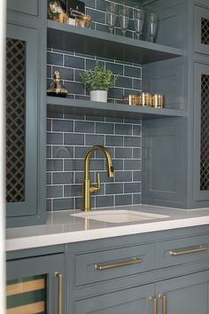 a kitchen with gray cabinets and gold faucet