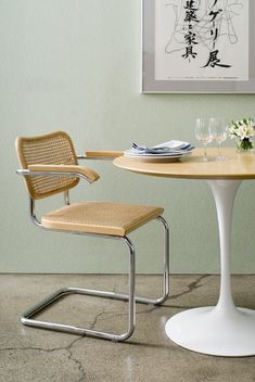 a table with two chairs around it and a vase on the table next to it