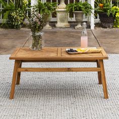 a wooden table sitting on top of a stone floor next to potted plants and flowers