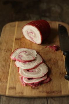 sliced up meat sitting on top of a wooden cutting board