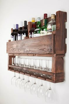 a wooden shelf with wine glasses and liquor bottles on the top, hanging from it's side