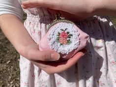 a person holding a small purse with flowers on it's side in their hands