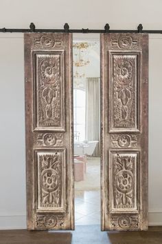 an ornately carved door is open to the living room, with a large mirror behind it