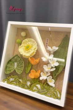 a white frame with flowers in it on a table