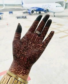 a woman's hand with henna on it and an airplane in the background