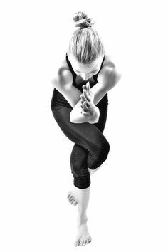 a woman in black and white is doing yoga