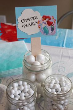 there are some little jars with white balls in them and a sign that says oyster pearls