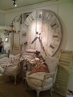 a large clock on the wall in a room with chairs and other furniture around it