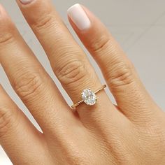 a woman's hand with a diamond ring on top of her finger and white nails