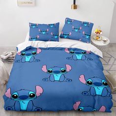 a bed covered in blue and pink sheets with cartoon characters on the comforter cover