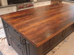 a kitchen island made out of wood in the middle of a floored area with an oven