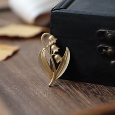 Show your unique style with this gorgeous Lily of the Valley Brooch. Delicately crafted from gold, this brooch is perfect for any occasion - from a casual day out to your wedding day. With eye-catching floral detail, this classy brooch will be sure to make a statement. 👌 M A T E R I A L • 18K Gold plated over brass• This product is hypoallergenic (nickel free) and tarnish resistant 📏 S I Z E • Length: 5.5 cm (2.16 inch)• Width: 3 cm (1.18 inch) Elegant Yellow Gold Enamel Pin Gift, Gold Flower Brooch Lapel Pin, Brass Brooch For Wedding, Brass Brooch Jewelry For Wedding, Brass Wedding Brooch, Elegant Gold Flower Lapel Pin, Flower-shaped Wedding Brooch, Flower Shaped Wedding Brooch, Wedding Enamel Pin Brooch