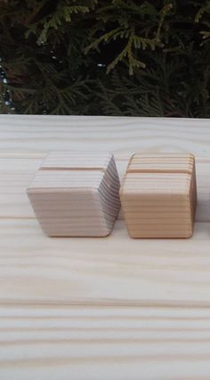 three wooden cubes sitting next to each other on top of a wood table with pine trees in the background