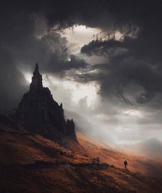 a person standing on top of a hill under a cloudy sky with dark clouds above