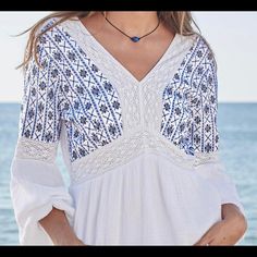 White Cotton With Cross Stitch Embroidery In Shades Of Blue. White Lace Inlays And Deep V Neck Front And Back. Elastic Sleeves With Decorative Ties. Makes Me Miss The Ocean!!! White V-neck Top With Intricate Embroidery, White Tops With Embroidered Hem For Beach, White Embroidered Hem Top For Beach, Blue V-neck Embroidered Top For Beach, Summer Beach Embroidered Top With Lace Trim, White Embroidered Top For Beach With Geometric Design, White Embroidered Top With Geometric Patterns For Beach, White Embroidered Top For Vacation, White Embroidered V-neck Top