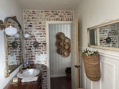 a bathroom with brick walls and wood floors, mirrors on the wall and a white sink