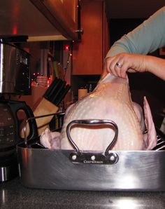 a woman is holding a turkey in a pan