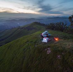 two tents set up on the side of a mountain at night with campfires