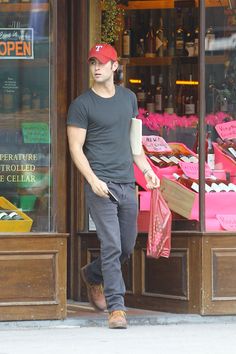 a man is walking out of a store holding a pink bag and looking in the window