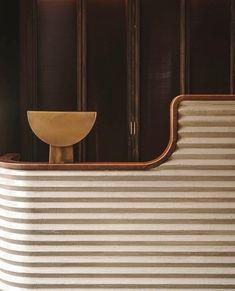 a chair sitting in front of a wall with wooden paneling on the side and a bowl next to it