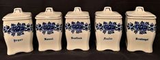 four blue and white ceramic canisters sitting next to each other on a black background