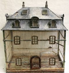 a doll house made out of wire and wood with windows on the top floor, in front of a white wall